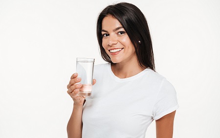 woman holding a glass of water and smiling