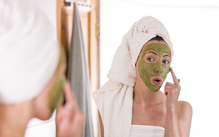 woman applying green tea mask on her face